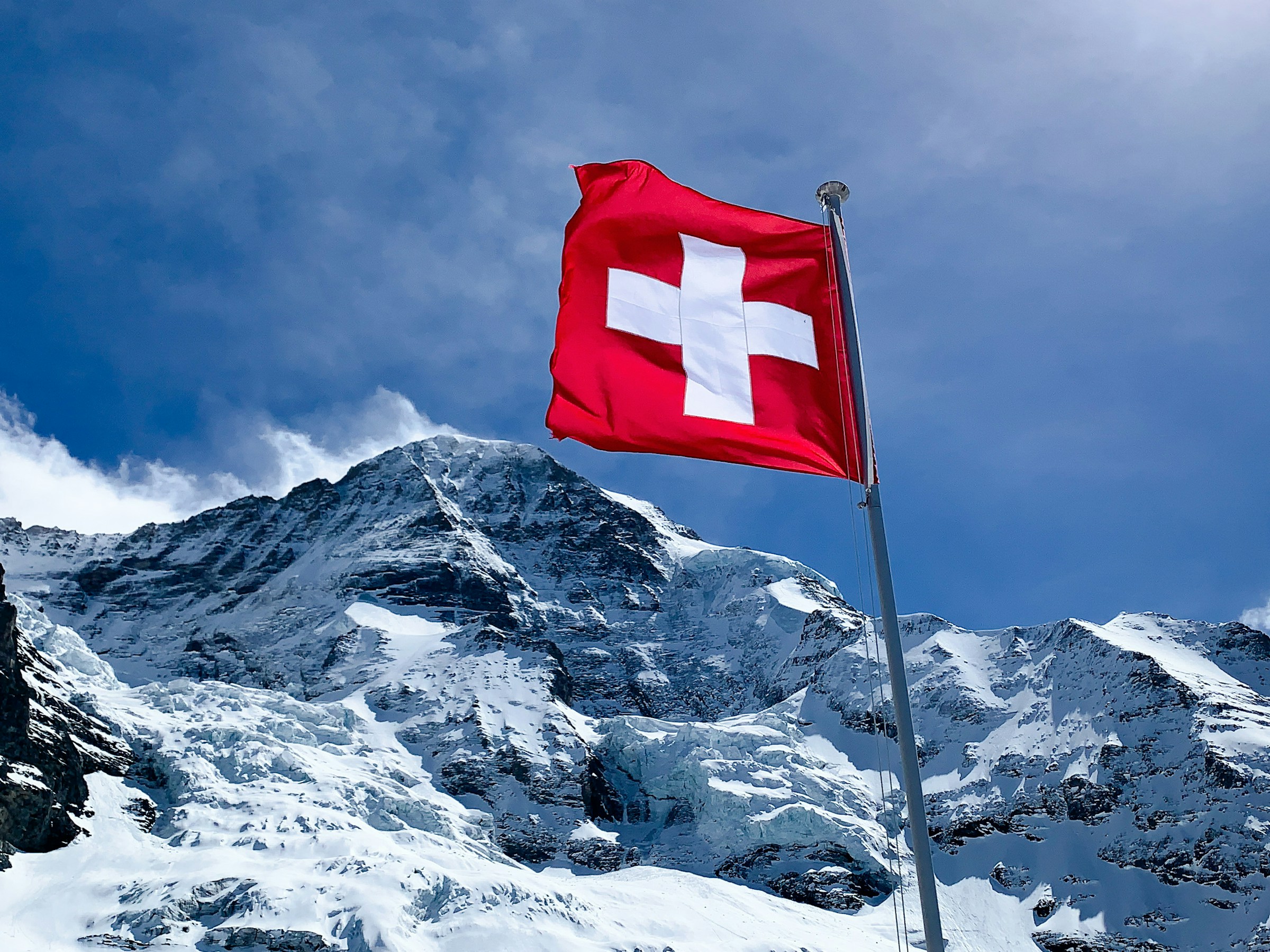 Swiss flag in front of the snow-covered Mönch above Grindelwald